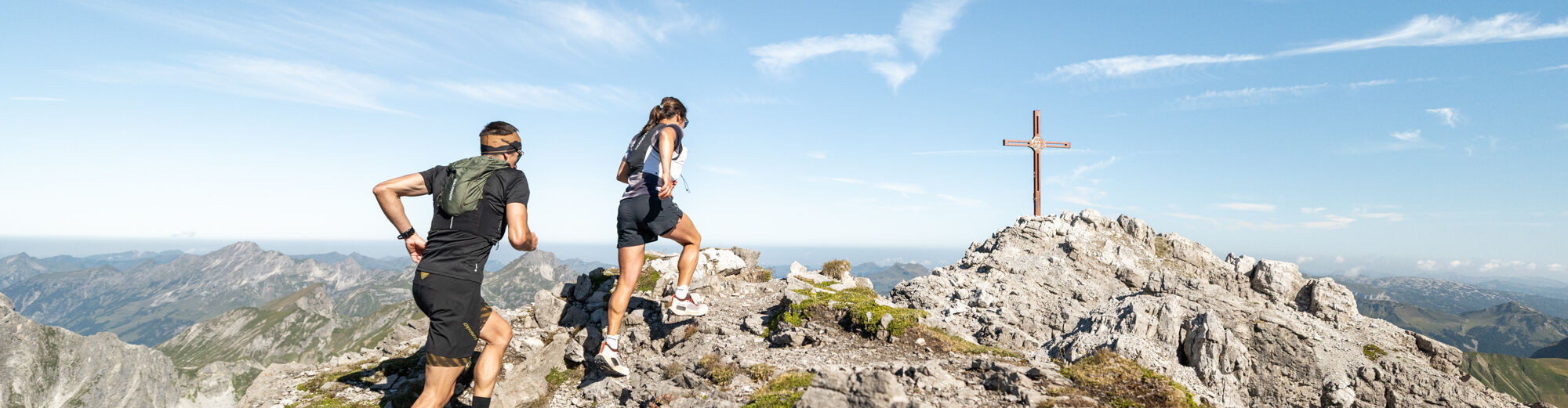 Zwei Trailrunner laufen die letzten Meter bis zum Gipfelkreuz der Mohnenfluh