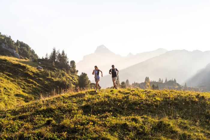 Zwei Trailrunner laufen durch die Berglandschaft von Lech 