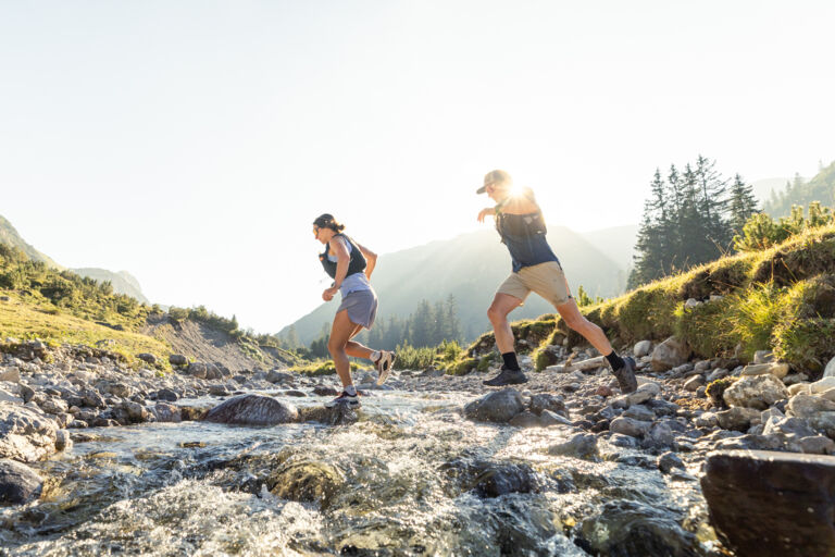 Zwei Trailrunner überqueren dynamisch den Lech